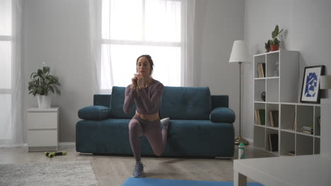 sexy-slender-woman-is-doing-physical-exercise-at-home-at-morning-time-squatting-on-one-leg-in-living-room-sporty-lady-in-interior-of-apartment